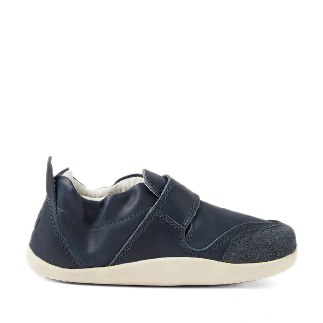 A single Bobux XP Explorer Ripple First Walker Navy 502509 shoe is displayed in a side view against a white background, featuring a navy blue slip-on design with a soft upper material, reinforced toe cap, and a flexible white sole., 42842, 9420068568563, 9420068568570, 9420068568587