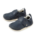A pair of Bobux XP Explorer Ripple First Walker shoes in navy, featuring beige soles, Velcro straps, and soft suede toe caps. These flexible-soled toddler shoes are perfect for first walkers and are displayed on a white background.