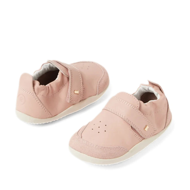 A pair of Bobux XP Explorer Ripple First Walker Cameo Rose 502603 baby shoes in soft pink (Cameo Rose), featuring flexible soles, white accents, velcro straps, and subtle gold embellishments, displayed side by side on a white background—perfect as stylish first walker shoes for your little one.