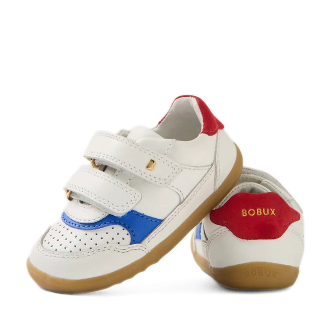 A pair of Bobux SU Step Up Hunter Leather Toddlers Sneaker in White Salsa, featuring white leather with blue and red accents, brown soles, and two velcro straps. Gold “BOBUX” branding appears on the heel and side, making these stylish first walker shoes ideal for little ones on the move.