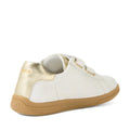 The Bobux Kid+ Plus KP Maverick Leather Sneaker in White Gold features a white upper, light brown sole, gold heel accent, and two velcro straps, shown from the back left—ideal for those looking for comfortable kids’ sneakers with an adjustable strap design.