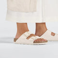 Beige Eggshell Birkenstock Arizona Double Strap  sandals worn with white pants on a light gray background.,
4066648369509,
4066648369547,
4066648369585,