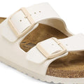 Beige sandal with a buckle on a white background close up strap and buckle dtail of Birkenstock arizona eggshell slide sandal.
4066648369509,
4066648369547,
4066648369585,