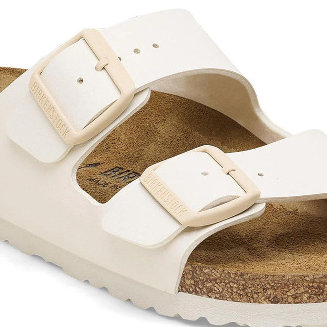 Beige sandal with a buckle on a white background close up strap and buckle dtail of Birkenstock arizona eggshell slide sandal.
4066648369509,
4066648369547,
4066648369585,