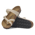 Pair of Birkenstock Mayari sandals with thin beige straps and a toe loop and cork soles on a white background