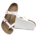 A pair of Birkenstock Mayari Womens Birko Flor sandals in white with a regular width, featuring two straps with buckles, a contoured footbed, and brown sole. One sandal stands upright while the other lies on its side.