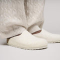 A person in textured cream pants and matching Birkenstock Amsterdam Felt Wool Clog Eggshell Off White (Regular Width) with cork-latex footbed, standing on a light surface., 51708, 51709, 4067707298440, 4067707298488, 4067707298525, 4067707298563, 51714, 51715, 51716, 51717, 51718