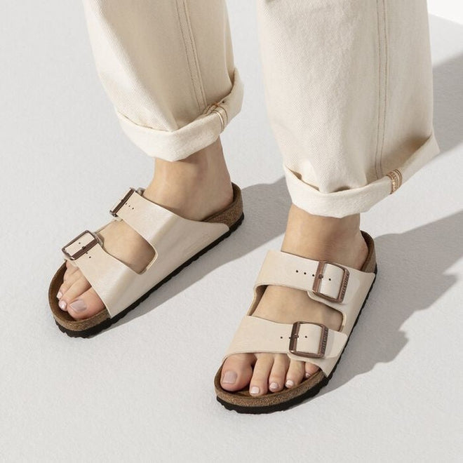 Arizona 2 strap sandals in a warm pearlised white with gold buckles on a woman wearing rolled up cream coloured pants with a top down view of both feet.,4044477107172,4044477107196,4044477107219,4044477107233,4044477107257,4044477107271,,,,,,,

