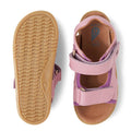 The Bobux IW Iwalk Strand Sandal in Lilas Pink is a toddler open-toe sandal with purple accents, adjustable Velcro straps, and tan rubber soles. One sandal is shown from the top; the other displays the sole's tread pattern., 9420068556942, 9420068556959, 9420068556966, 9420068556973, 9420068556980