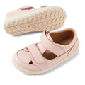 A pair of Bobux IW Iwalk Troop Toddlers Leather Sandal in Cameo Rose Pink, with Velcro straps and beige textured rubber soles, is displayed—one upright and the other showing the sole.