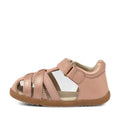 The Bobux Step Ups Cross Jump Dusk Pearl Pink Closed Toe Sandal is a pink toddler sandal featuring a closed heel, open toe, and multiple straps across the front. It has a Velcro ankle strap and a brown rubber sole., 9420062083222, 9420062083239, 9420062083246, 9420062083253