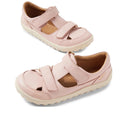 The Bobux Kid+ Troop Leather Closed Toe Sandal in Cameo Rose Pink features a wide toe box, adjustable Velcro straps, beige soles, and perforations for breathability. These barefoot kids sandals are shown against a white background.