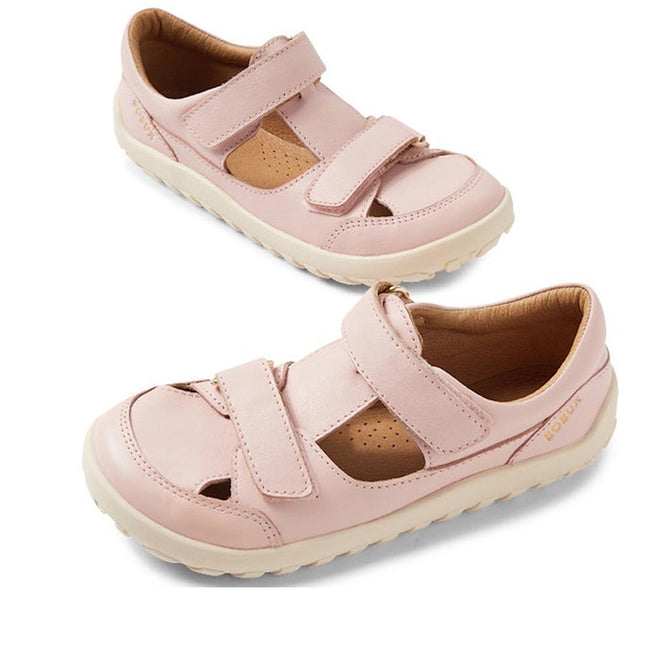 The Bobux Kid+ Troop Leather Closed Toe Sandal in Cameo Rose Pink features a wide toe box, adjustable Velcro straps, beige soles, and perforations for breathability. These barefoot kids sandals are shown against a white background.