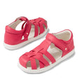 Two Bobux Kids Plus KP Tropicana II Radiant Raspberry Sandals with white soles are displayed—one upright, one lying down. These unisex sandals feature closed toes, woven leather straps, and hook-and-loop closures for style and comfort.