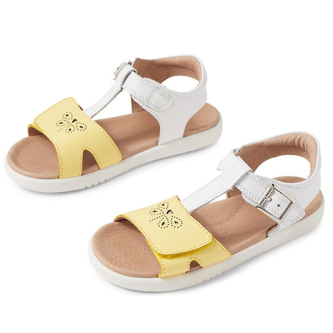 The Bobux Kids + Plus Girls Haven White Pale Banana sandals feature white adjustable ankle straps with silver buckles, yellow front straps with butterfly cutouts, cushioned tan insoles, and white soles for comfort.