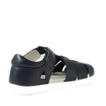The Bobux Kid+ Plus Tidal Closed Toe Quick Dry Sandal Navy 834404A is shown from the back, featuring a navy blue design with a closed heel, open sides, and a contrasting white sole. This sandal has a closed toe, secure Velcro strap, and multiple horizontal bands across the upper for enhanced comfort and support.