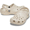 The Crocs Adults Classic Animal Clog in Almond Tint Leopard features a beige color with a subtle animal print, ventilation holes, and adjustable heel straps, displayed on a white background.
