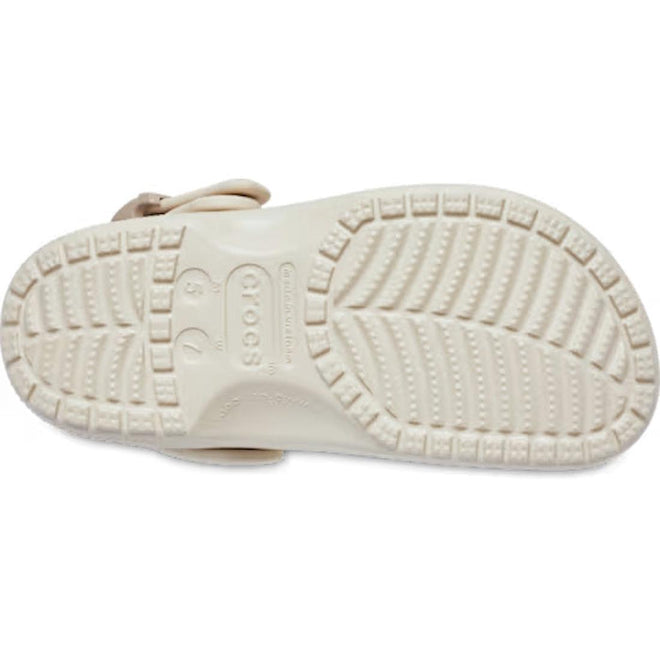 The image displays the sole of the Crocs Adults Classic Enamel Buckle Clog Frappe, a light-toned sandal with deep grooves, circular grip textures, and visible size and brand details. Crafted from Croslite foam for classic Crocs comfort., 198445415944, 198445415951, 198445415968, 198445415975, 198445415982, 198445415999