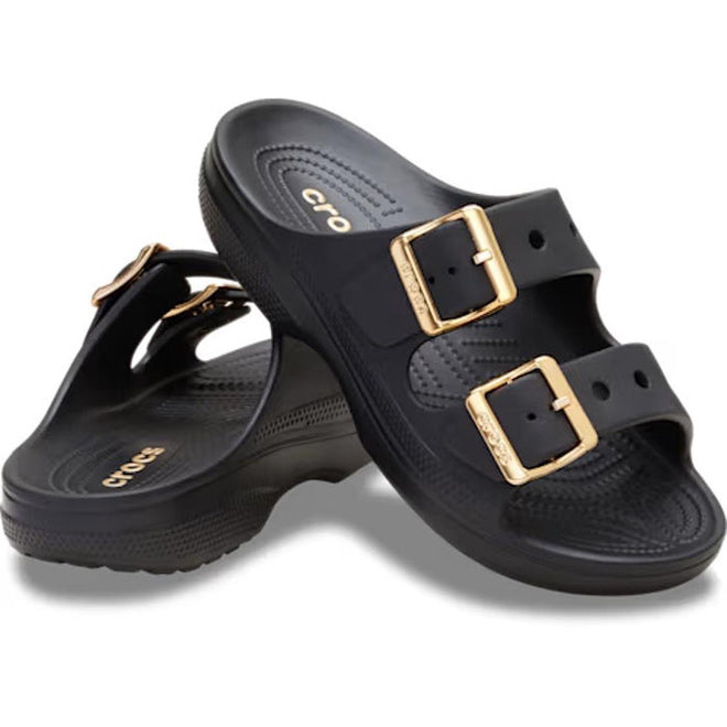 The Crocs Womens Classic Metallic Buckle Saturday Sandal Slide in black features two adjustable straps with shiny gold buckles, a textured footbed for Crocs Comfort, and the signature logo.