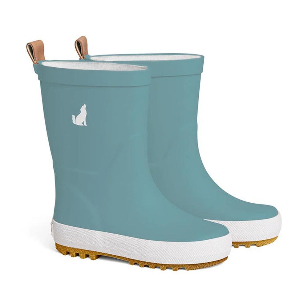 A pair of CryWolf Rain Boots in Stone Blue for children, crafted from natural rubber on clearance and not returnable, featuring white soles, tan treads and pull tabs, and a small white howling wolf silhouette near the top of each boot.