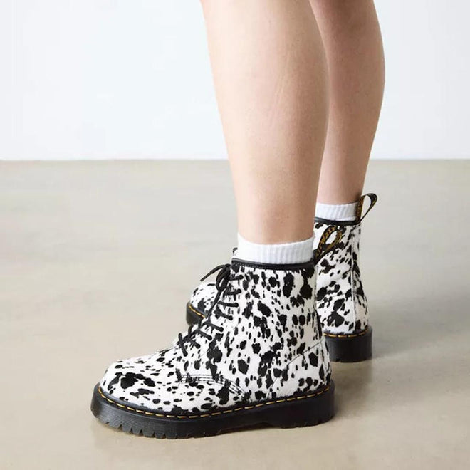 Wearing Dr Martens 1460 Bex Dalmatian Hair On Leather Lace Up Boots with white socks, standing on a light-colored floor against a plain white wall., 190665780307, 190665780314, 190665780321, 190665780345, 190665780352, 51690