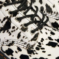 Close-up of the Dr Martens 1460 Bex Dalmatian Hair On Leather Lace Up Boot, featuring black laces, a white upper with black and brown cow-print spots, detailed stitching, eyelets, and a durable Goodyear welted sole., 190665780307, 190665780314, 190665780321, 190665780345, 190665780352, 51690