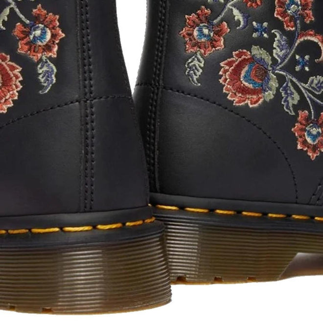 Close-up of the heels of two Dr Martens 1460 Vonda TF Tavern Floral Genix Nappa Leather boots, showing thick brown soles, yellow stitching, and colorful red, blue, and green embroidered floral designs., 47991, 190665742619, 190665742626, 190665742633, 190665742657, 47996, 47997