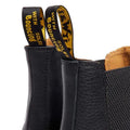 Close-up of the Dr Martens 2976 Ambassador Black Leather Chelsea Boot with yellow and black pull tabs reading WITH BOUNCING SOLES, Goodyear-welted stitching, and textured black leather details visible., 50056, 50057, 50059, 190665663303, 190665663310, 190665663327, 50067, 50068