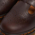 Close-up of the Dr Martens 8065 2 Strap Mary Jane Shoe in Crazy Horse Brown, showing dual buckles, decorative toe perforations, and signature yellow stitching on the black rubber sole., 190665588941, 190665588958, 190665588965, 190665588972, 13164654654, 190665588996, 190665589009, 190665589016