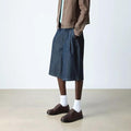 A person in a brown jacket, light green shirt, knee-length wide denim shorts, white socks, and Dr Martens Brookline Lo Dark Brown Crazy Horse Leather Shoe with SoftWair insole stands on a light floor against a plain background. Face not visible., 52062, 52063, 52064, 190665753912, 190665753936, 190665753943, 190665753950, 52069, 52070, 52071