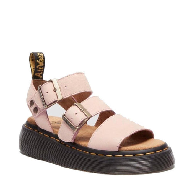 The right foot front and side view of Dr Martens Gryphon platform quad Pink sandal with black sole on a white background. Features ankle strap with a bucklen fastening and a strap over the top of the foot with a buckle and another strap over the toes. The footbed is tan and cushioned.