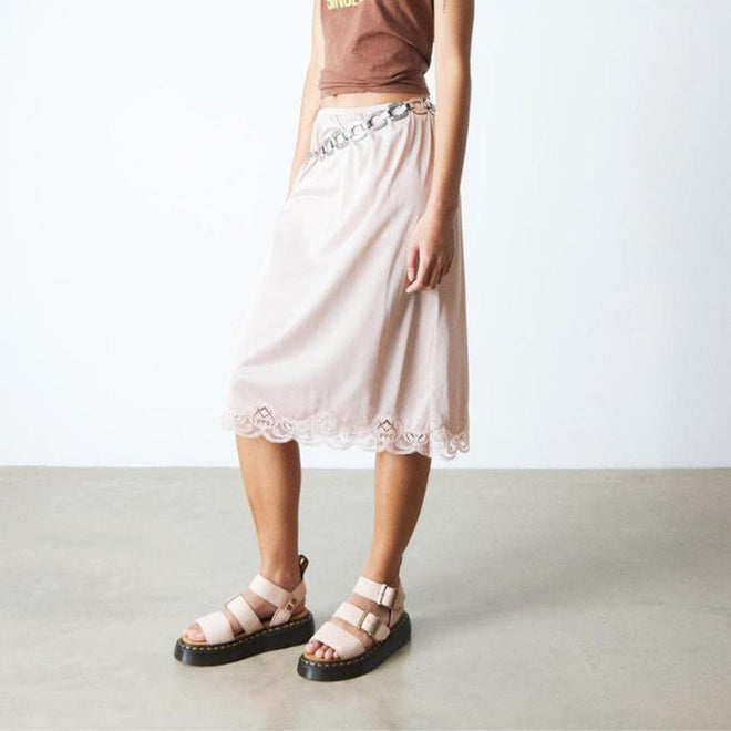 Person wearing a pink skirt with lace details showing the Dr Martens Grphon Quad sandals in pink on a plain background.,
190665714630,
190665714647,
190665714661,