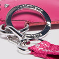 Close-up of silver keychain Dr Martens Heart Charm with pink tassel against a pink background.,
190665739800,