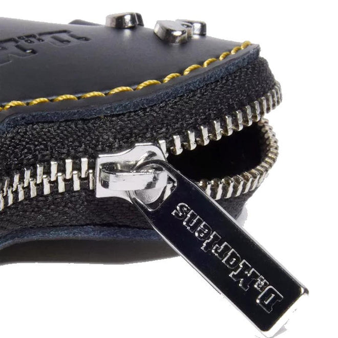 Close-up of a black leather Dr Martens small bag charm  with a silver zipper and visible brand name on a white background.
190665739794,