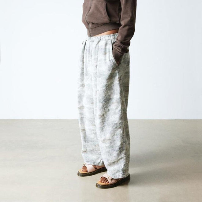 Person wearing white patterned pants and a brown top and Dr Martens Pink Josef slide sandals on a plain background,
190665707533,
190665707540,
190665707557,
190665707571,
190665707588,