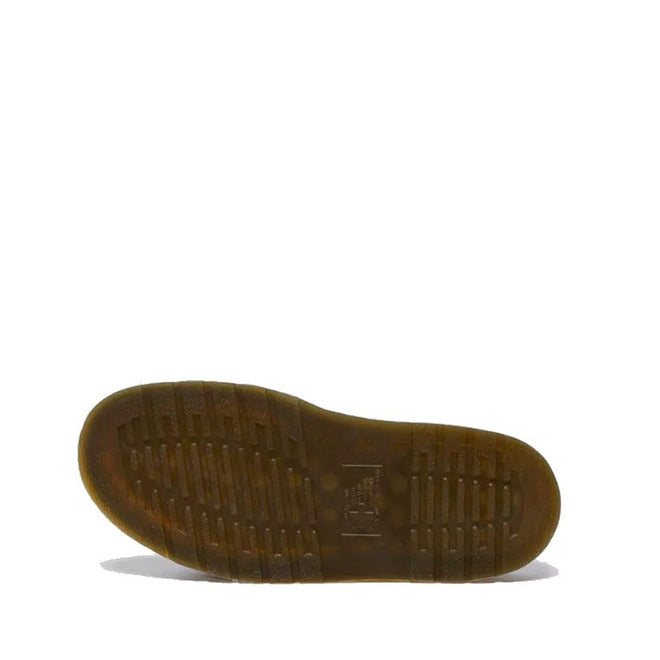 The Dr Martens Josef Slide Sandal Cashew Ambassador Leather is shown from the bottom, highlighting its rubber sole with a textured grip pattern of horizontal and vertical grooves in tan brown against a white background.