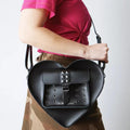 A side view of a women carrying the dr martens heart bag over her shoulder, showing the size
190665728408