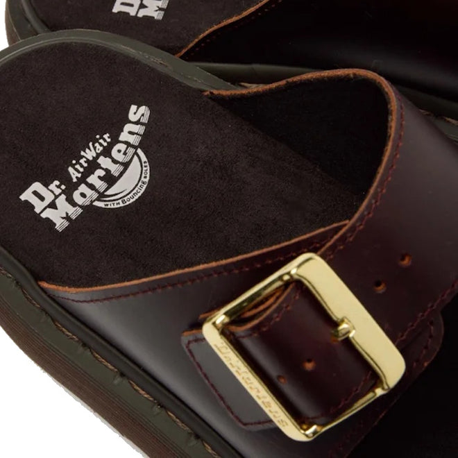 Close-up of the Dr Martens Josef Charro Atlas Slide Sandal Leather in dark brown, showcasing a gold buckle and a visible white logo on the black cushioned insole.