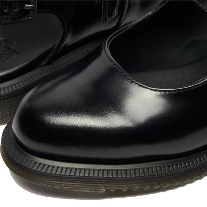 Close-up of Dr Martens Madaline Black Smooth Womens Slingback Mary Jane Shoes, featuring black polished leather, rounded toes, thick rubber soles, detailed stitching, and a smooth texture.