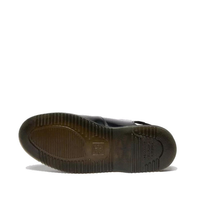 The underside of a Dr. Martens Madaline Black Smooth Womens Slingback Mary Jane shoe shows a translucent, textured rubber sole with grooves, ridges, and a central rectangular logo, set against a plain white background.