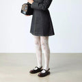 A person in a dark dress and white lace-patterned tights stands on a light floor, holding a small leopard-print handbag. They wear Dr. Martens Madaline Cherry Red Arcadia Women's Slingback Mary Jane Shoes; their face is not visible.
