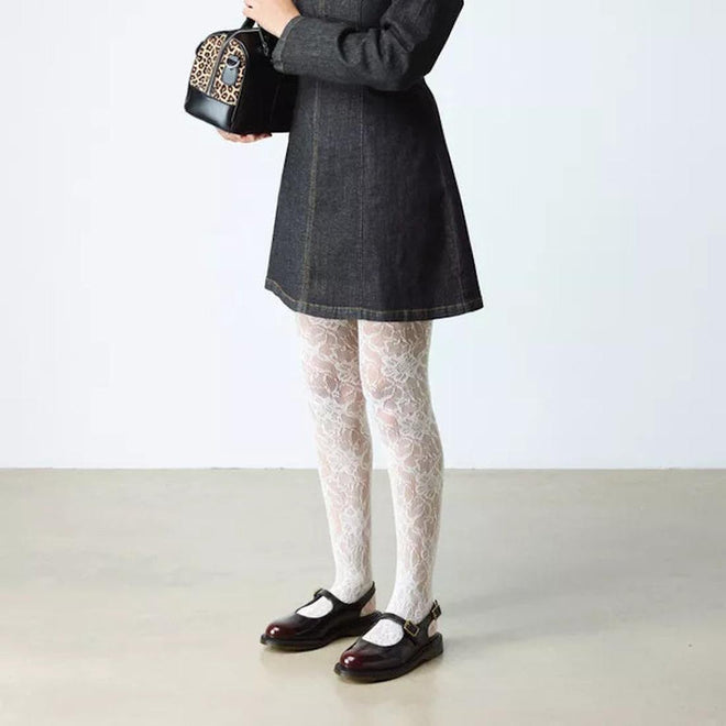 A person in a dark dress and white lace-patterned tights stands on a light floor, holding a small leopard-print handbag. They wear Dr. Martens Madaline Cherry Red Arcadia Women's Slingback Mary Jane Shoes; their face is not visible.