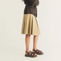 A person wearing a tan pleated skirt and Dr Martens Wrenlie Flower Open Toe Dark Brown Grizzly Quad Sandal, featuring floral cutouts and a Quad Shore sole., 54784, 190665777352, 190665777369, 190665777383, 54788, 54789