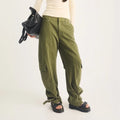 A person wearing olive green cargo pants and black Dr Martens Zebzag Black Pisa Leather 3 Strap Sandal, carrying a black handbag.