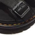 Close-up of a Dr Martens Zebzag Black Pisa Leather 3 Strap Sandal strap secured by a metal buckle, featuring yellow contrast stitching along the air-cushioned sole.