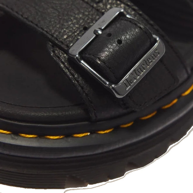 Close-up of a Dr Martens Zebzag Black Pisa Leather 3 Strap Sandal strap secured by a metal buckle, featuring yellow contrast stitching along the air-cushioned sole.