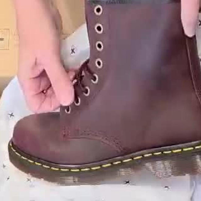 A person is lacing up a Dr Martens 1460 Cherry Red Crazy Horse Waxy Leather 8-eye Boot with yellow stitching on the Goodyear Welted sole, resting on white tissue paper with small black stars., 190665786835, 190665786842, 190665786859, 190665786873, 190665786880, 190665786897, 190665786910, 50000, 50001, 50002