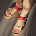A person wearing the Woden Line Women's 3 Strap Sandal in Flame Multi Red—with pink straps across the toes and bright red ankle straps—stands on a smooth, sunlit surface. These comfortable sandals are an essential addition to any summer wardrobe., 5713326706673, 5713326706680, 5713326706697, 5713326706703, 5713326706710, 5713326706727, 5713326706734