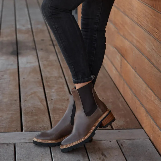 EOS Linear women’s boot in mid brown leather with side gussets, block heel, and lugged sole. Side View of left Foot on a model