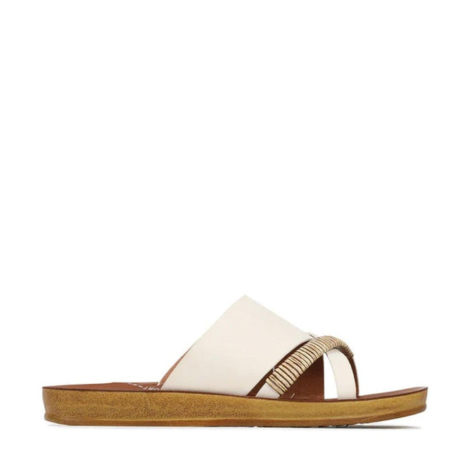 Side view of the Los Cabos Bride Bone Flat Women's Slide Sandal, featuring a tan sole, wide white crisscross leather strap, and decorative beige woven toe detail—perfect for resort wear, shown against a plain white background.